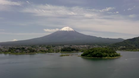 Aerial-flying-towards-iconic-and-majestic-volcano-Mount-Fuji-with-scenic-landscape,-lake-Kawaguchi,-and-snow-capped-peak-in-Fuji,-Japan