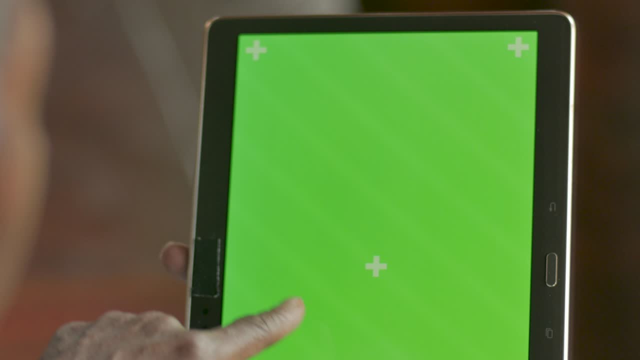 la mano de una mujer negra deslizando, tocando y tocando una pantalla verde de una tableta