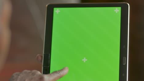 la mano de una mujer negra deslizando, tocando y tocando una pantalla verde de una tableta
