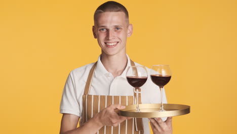 un tipo sonriente sosteniendo una bandeja con vasos de vino
