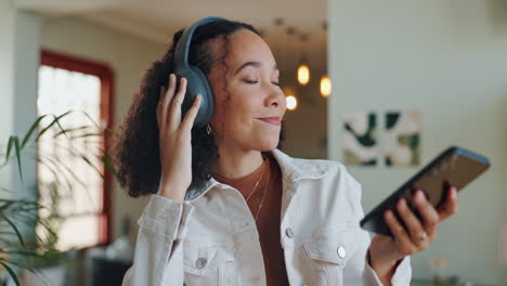 woman listening to music on headphones while using her mobile phone at home