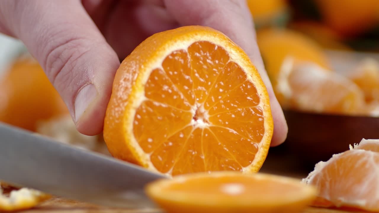 mano masculina con un cuchillo cortado de piezas redondas de mandarina.
