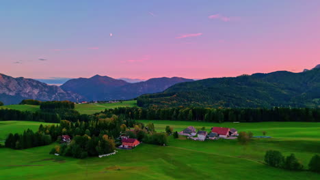 Foto-Panorámica-De-Un-Terreno-Con-árboles-Y-Pocas-Casas-Montañas-Visibles-En-La-Distancia-Con-Cielo-Rosa