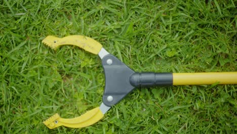 a yellow pincher on the grass,forceps,tongs,clamp,pliers lying on the grass