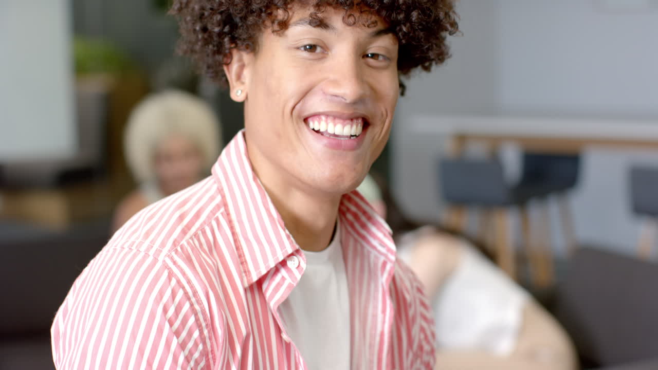 Giovane sorridente in camicia a righe che si diverte con gli amici all'interno