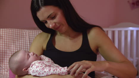 mother at home cuddling sleeping newborn baby in nursery