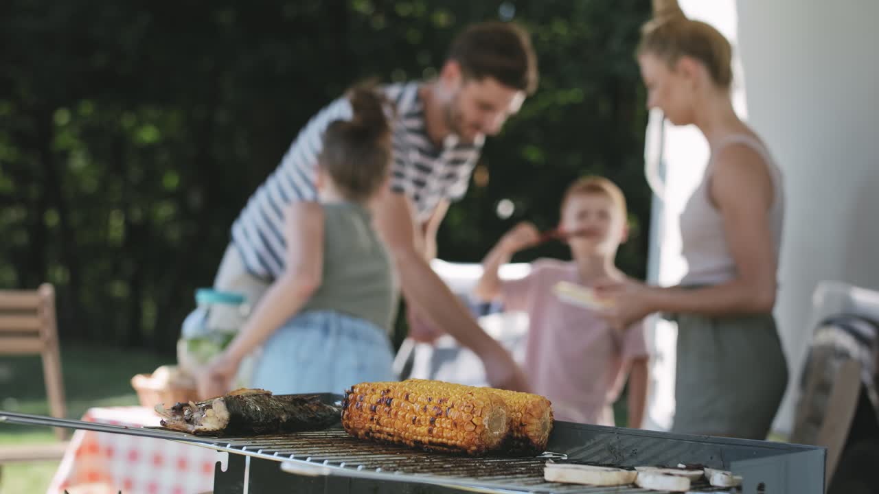 Video di pannocchie grigliate sullo sfondo di una famiglia vivace.