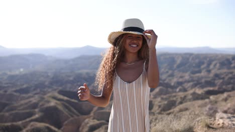 young woman in a striped dress and hat enjoying a scenic desert landscape