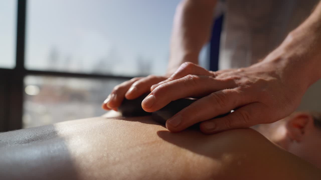 Nærbillede af hot stone massage på en kvindes ryg i et spa