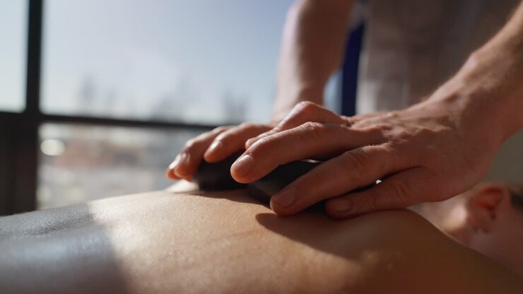 Nærbillede af hot stone massage på en kvindes ryg i et spa