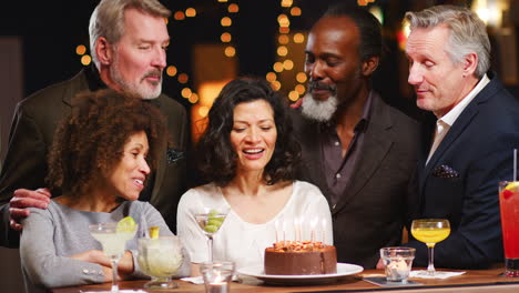grupo de amigos de mediana edad celebrando su cumpleaños en un bar
