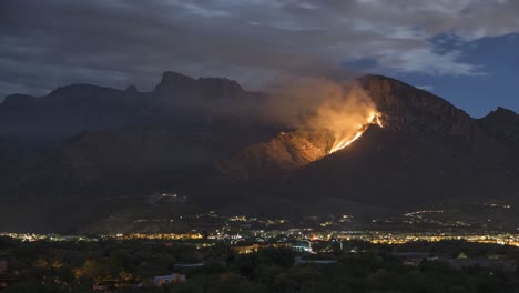 timelapse of clouds moving above wildfire and city lights at night