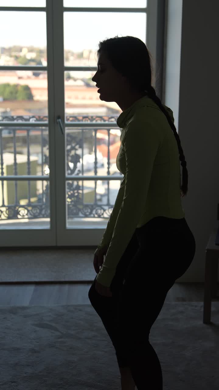 Woman in profile view, practicing yoga or exercise in a room
