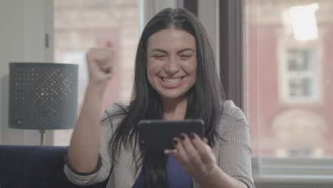 young attractive woman watches her team win a match and wins online bet - ungraded