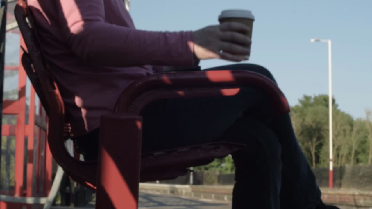 Woman waiting on train platform with coffee medium panning shot