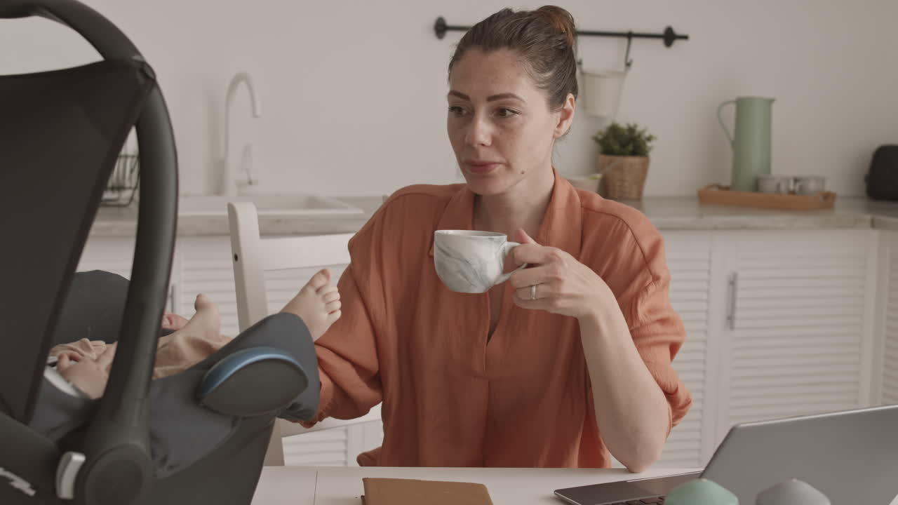 Young Mother Babysitting and Receiving Phone Call