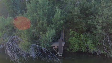 An-old,-wooden-dock-on-the-Russian-River-in-California-from-which-to-fish-or-launch-small-vessels---aerial-parallax-view-with-lens-flare