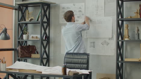 stylish office in loft style. businessman makes notes on the wall. business idea thinking design mind map. designer works in loft office and makes notes on the drawings on the wall.