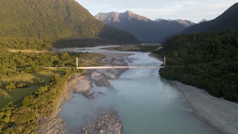 remote bridge crossing glacial stream in mountains at sunrise