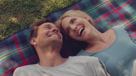 couple lying down on picnic blanket in the park on sunny day