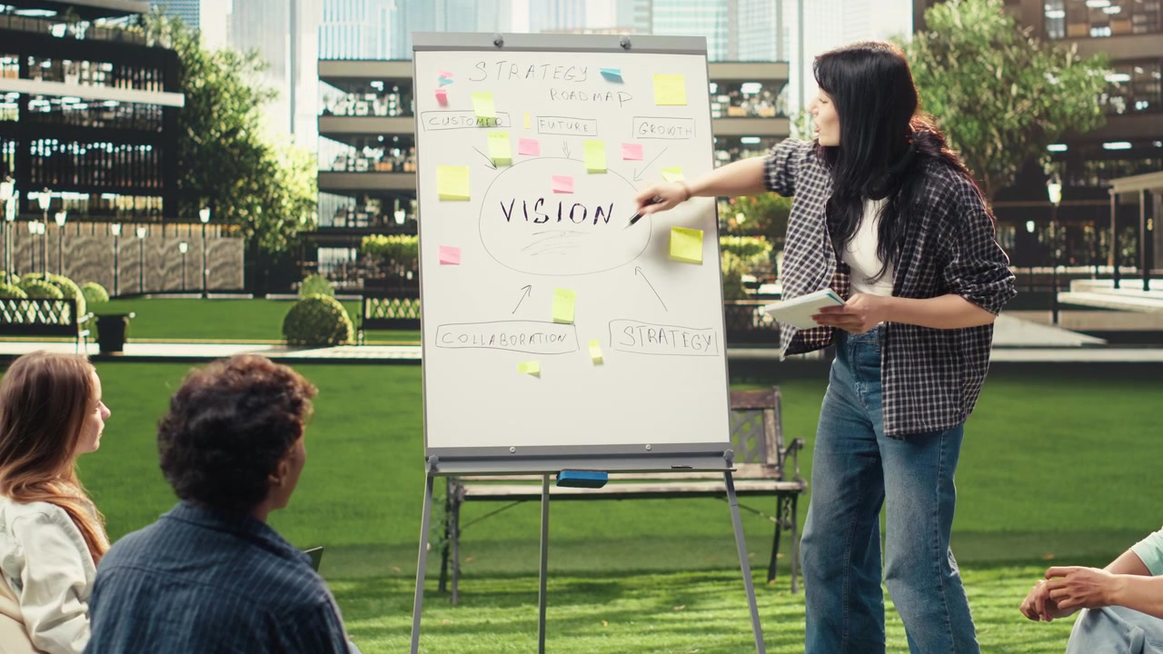Woman presenter standing beside whiteboard and pointing at information