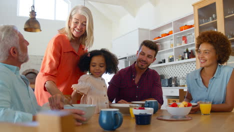 Familia-Multigeneracional-En-Casa-Disfrutando-Del-Desayuno-Sentados-Juntos-Alrededor-De-La-Mesa