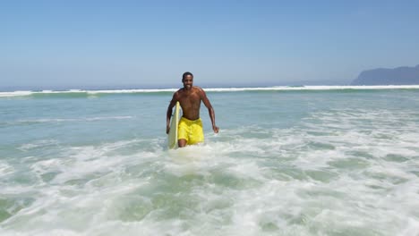 surfista masculino caminando con una tabla de surf en la playa 4k