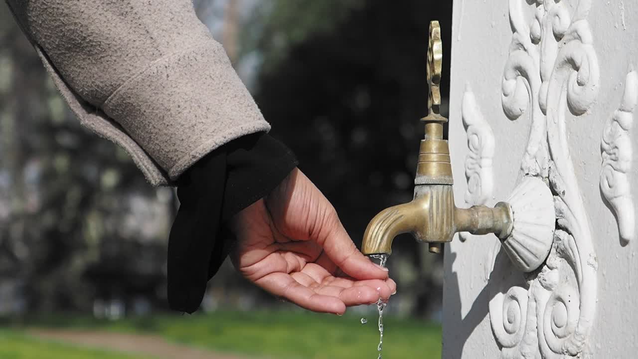 Person drinking water from a vintage fountain