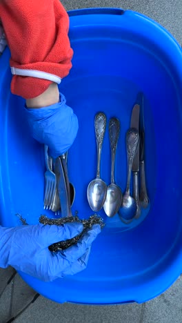 cleaning silverware in a plastic basin