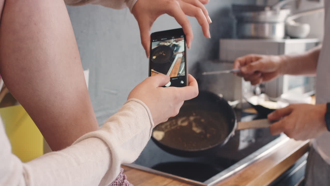 tomar fotos usando el teléfono inteligente del desayuno cocinando mantequilla de sartén para los medios sociales estilo de vida en casa en la cocina