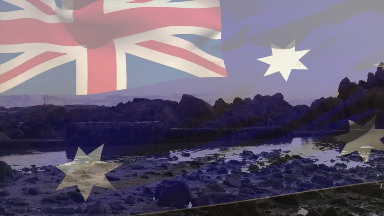 Waving Australian flag over rocky coastal landscape during dusk with animation