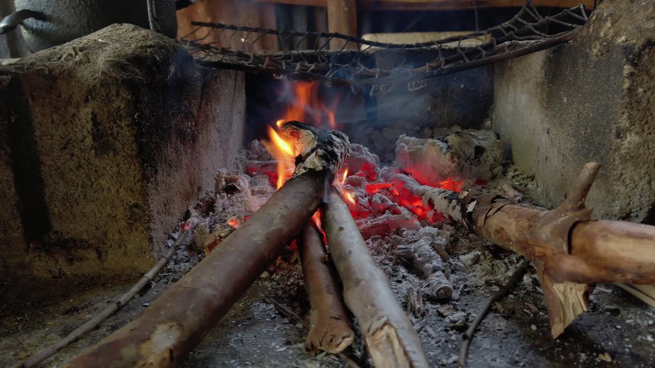 요리에 사용되는 시멘트 블록의 작은 좁은 화덕에서 타고 있는 진짜 야외 장작불과 불씨, 휴대용 팬을 닫습니다