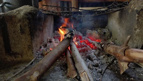 auténtico fuego de madera al aire libre y brasas ardiendo en bloques de cemento pequeña hoguera estrecha utilizada para cocinar, cierre la sartén de mano