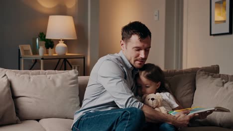 father reading book to daughter
