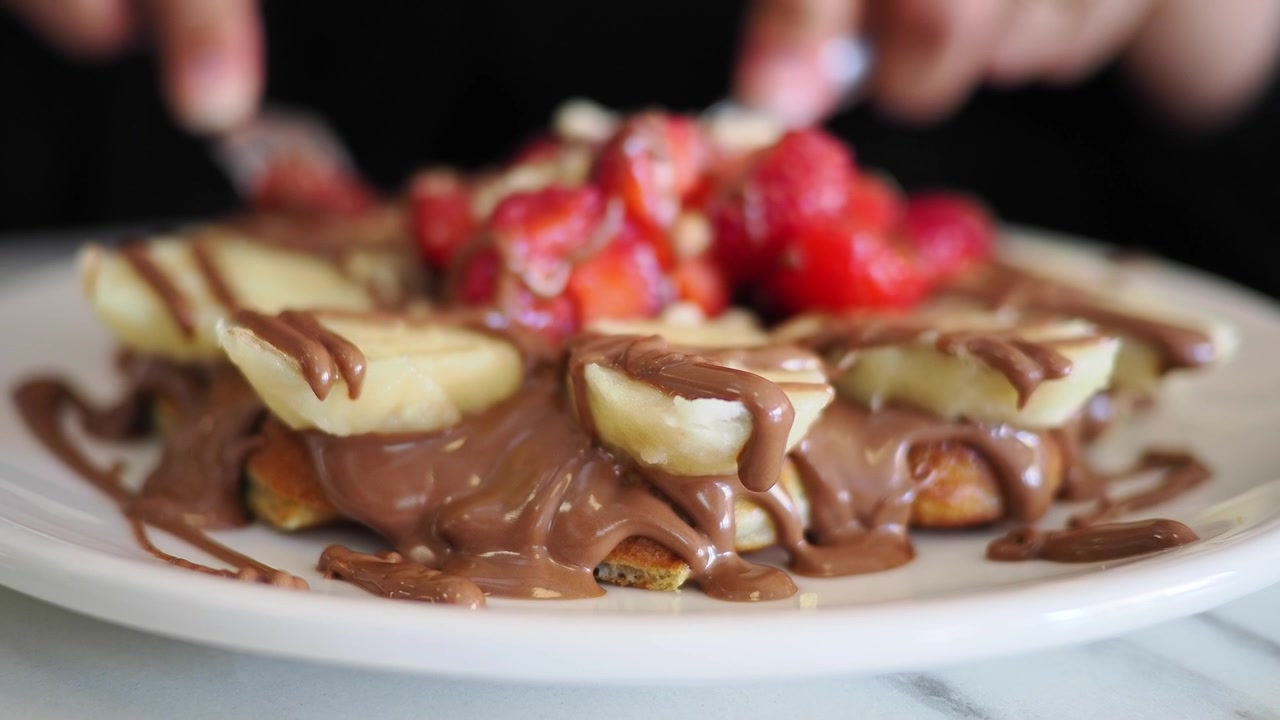 Pessoa Comendo Waffle Coberto com Chocolate, Bananas e Morangos