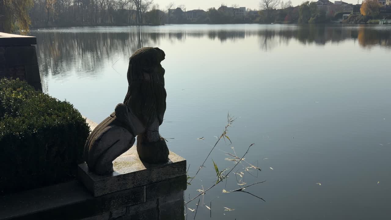 루마니아 모고소아이아의 잔잔한 호수를 내려다보는 돌 statues가 해돋이 빛에 비치고 있어요