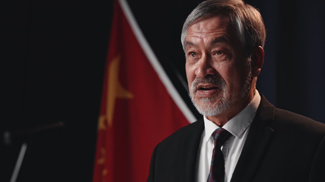 Political Figure Speaking at Press Conference with Chinese Flag