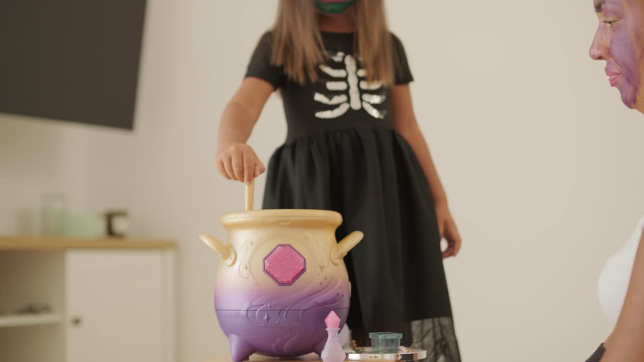 niña con disfraz de bruja jugando con su madre embarazada en halloween