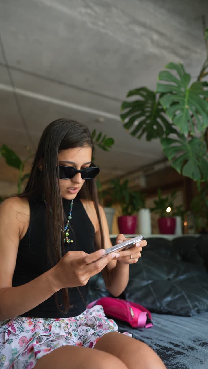mujer joven usando un teléfono inteligente en un ambiente interior acogedor