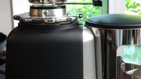 utilizing a top-tier burr grinder to process freshly roasted coffee beans into a medium consistency. pulverizing premium coffee beans in a sleek, industrial-grade black perfect hot cup of hot coffee..
