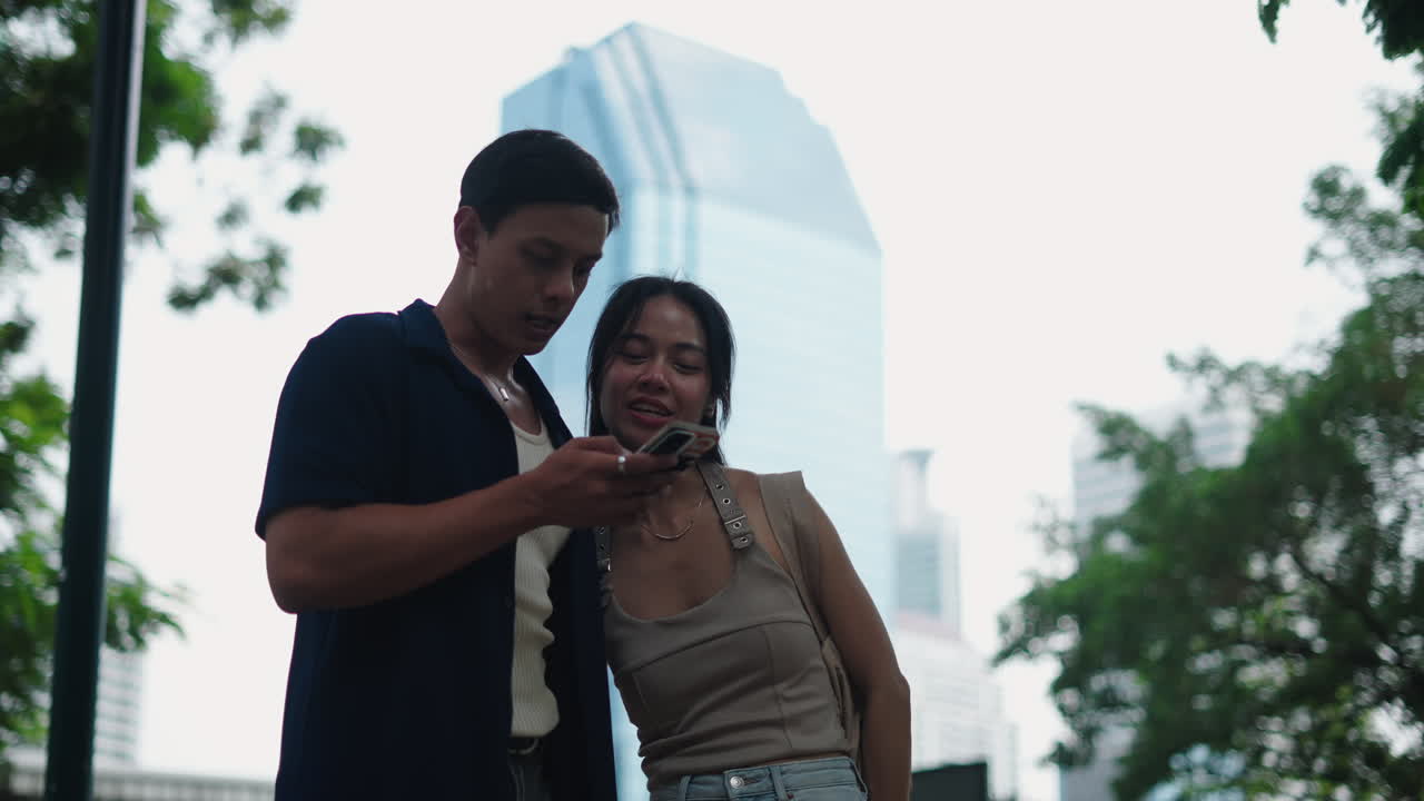 Coppia che guarda uno smartphone in un parco urbano