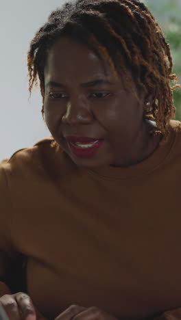 focused african american student looks in laptop getting distracted by girl friend. young woman with dyed hair looks for information for report closeup