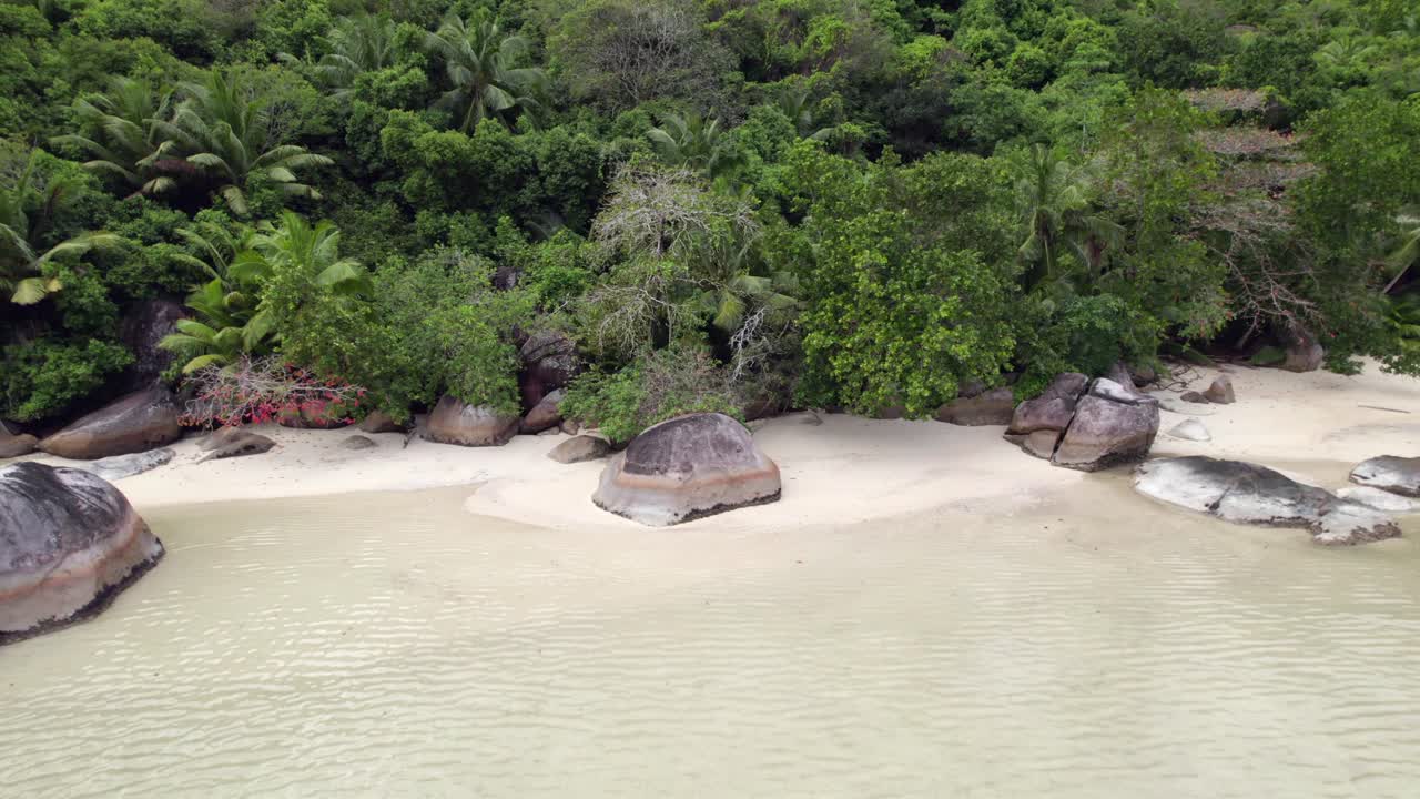 Drone footage of cap ternay beach, near granite stone and trees at low tide, Mahe, Seychelles 30fps 7