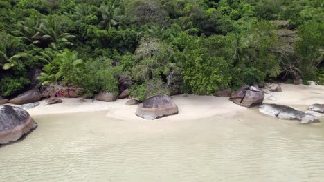drone footage of cap ternay beach, near granite stone and trees at low tide, mahe, seychelles 30fps 7