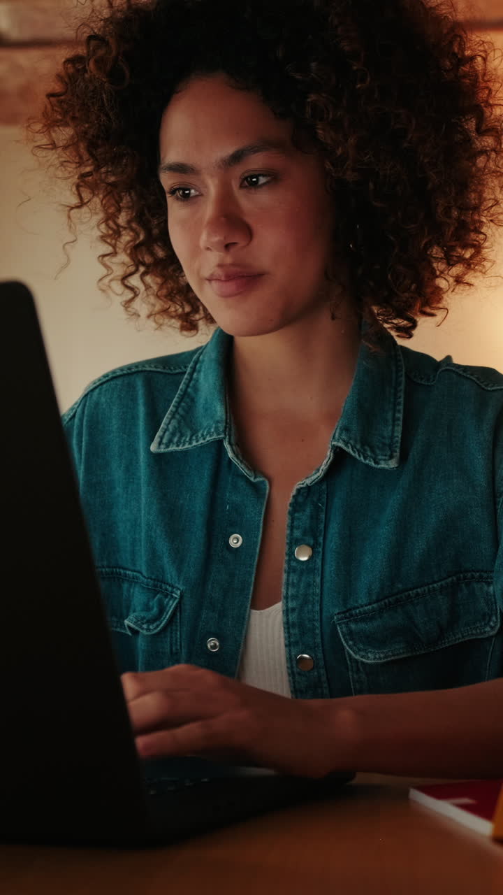 Smiling Young Woman with Curly Hair Using Laptop