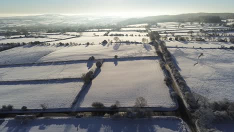 Frío-Invierno-Nevado-Británico-Patchwork-Tierras-De-Cultivo-Campo-Rural-Escena-Aérea-Al-Amanecer-Descenso-Hacia-La-Derecha