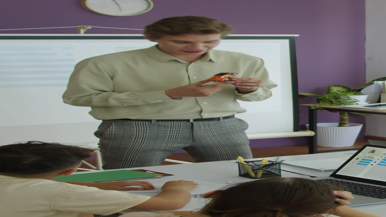 Insegnante che spiega i principi del funzionamento dei robot durante una lezione di informatica con bambini