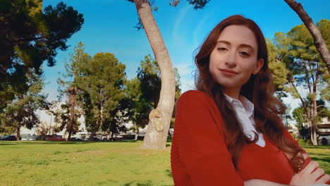 una mujer feliz, atractiva, joven, caucásica en el parque mirando a la cámara - contenta, segura de sí misma, un poco presumida