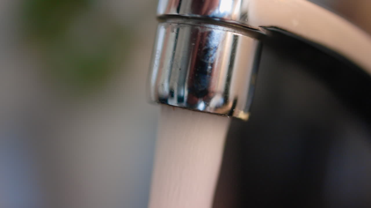 Tap water flowing out in a close-up of a sink's nozzle