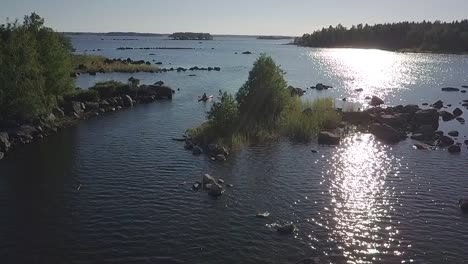 Disparo-De-Drones-En-Cámara-Lenta-De-Un-Hombre-En-Kayak-En-Aguas-Reflejadas-Por-El-Sol-En-Un-Archipiélago-Rocoso,-Ostrobotnia,-Finlandia